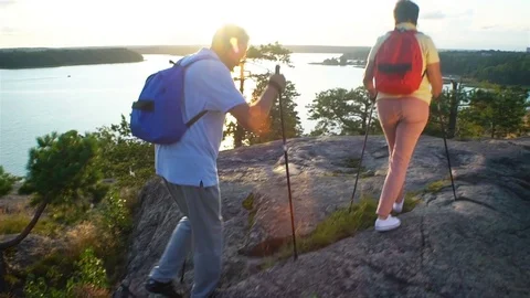 Elderly active couple climbing on the rock and admiring the sunrise, the sunset. Stock Footage 80224650
