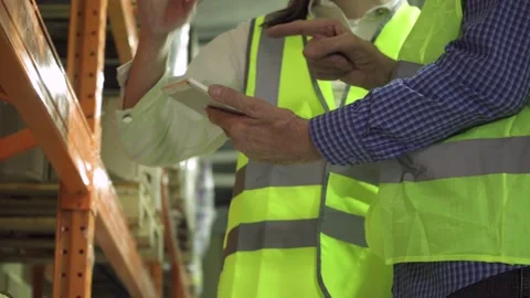 Elderly and young employees with a computer tablet working in a warehouse. Stock Footage 190480298