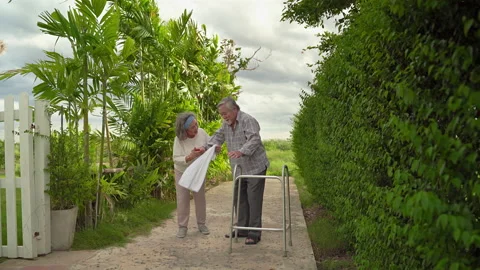 An elderly Asian man is using a walker to learn to walk around a walkway Stock Footage 136660790