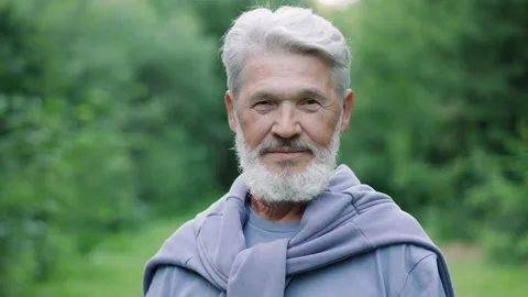 Elderly beard old man portrait in forest nature park. Grandpa face look camera. Video stock 231178876