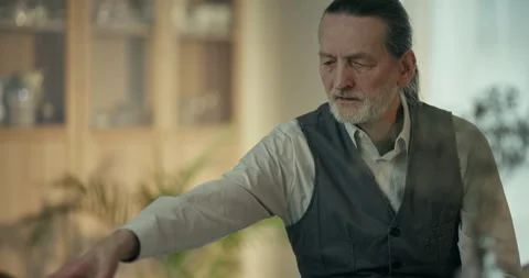 Elderly bearded man sitting in a warm home interior and looking aside 스톡 동영상 336288839