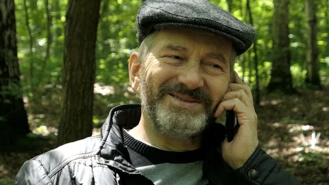 Elderly Bearded Man Talking On The Mobile Phone Sitting On The Bench In The Fore Stock Footage 90858676