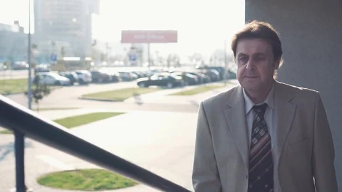 An elderly businessman in a jacket and tie climbs the stairs in the city. Slow Stock Footage 101509472