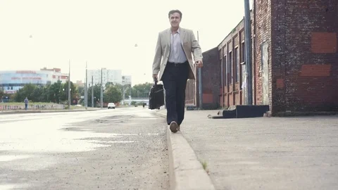 Elderly businessman in a jacket with briefcase have fun, walking on the border Stock Footage 101505939