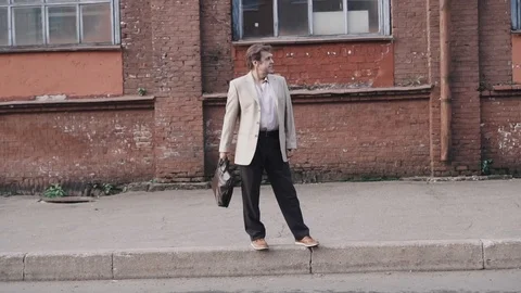 An elderly businessman in a jacket with a briefcase is standing on the edge of Stock Footage 101505687