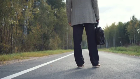 An elderly businessman in a jacket with a briefcase is standing on the road, and Stock Footage 101506203