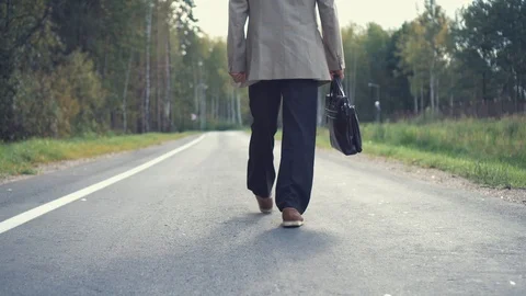 An elderly businessman in a jacket with a briefcase is walking along the road Stock Footage 101507211