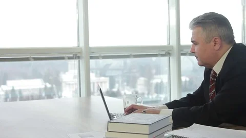 Elderly businessman working at a computer and drinking tea. Thinks looks out the Stock Footage 71028657