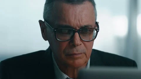 Elderly businessman working with computer in modern office.  he takes off his Видео 60767093