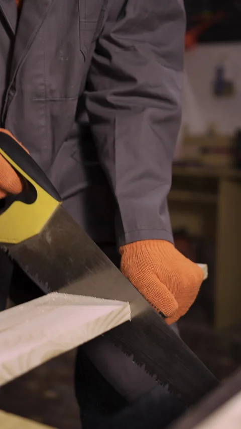 Elderly carpenter using sharp metal hand saw to cut wooden items works in his Vídeos de archivo 281658594