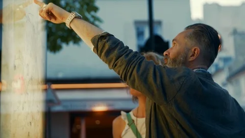An elderly, classy man standing next to his date and pointing at a map downtown Stock Footage 120185675