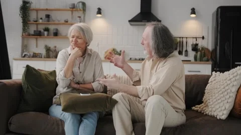 An elderly couple is arguing while sitting on the couch at home; an aggressive Stock Footage 262239110