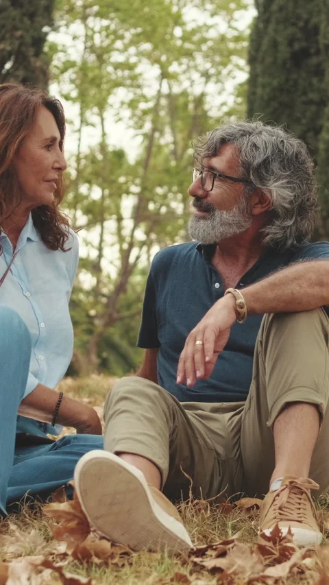 Elderly couple chatting while sitting on the grass in the park Stock Footage 255505530