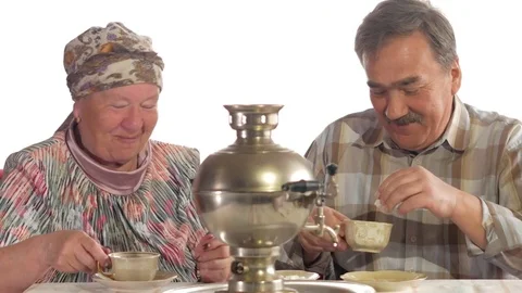An elderly couple is drinking tea from a vintage Russian kettle samovar. A man Stock Footage 74810030