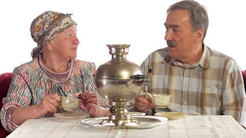 An elderly couple is drinking tea from a vintage Russian kettle samovar. A man Stock Footage 74810509