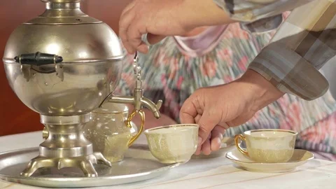 An elderly couple is drinking tea from a vintage Russian kettle samovar. A man Stock Footage 74810947