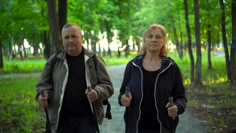 An elderly couple is engaged in Nordic walking in the forest. A man and a woman Stock Footage 200848465