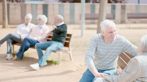 Elderly couple flirting while sitting on bench in courtyard 스톡 동영상 345553341