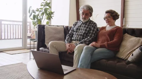 An elderly couple has difficulty using a modern laptop. Happy mature couple Stock Footage 244120921