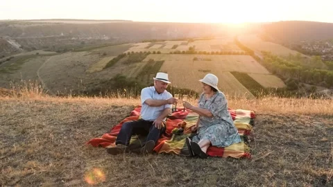 Elderly couple having a date on the top of the hill, drink champagne. Stock Footage 139045786