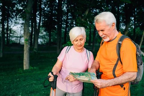 Elderly couple hikers checking map in sunny woods 写真素材