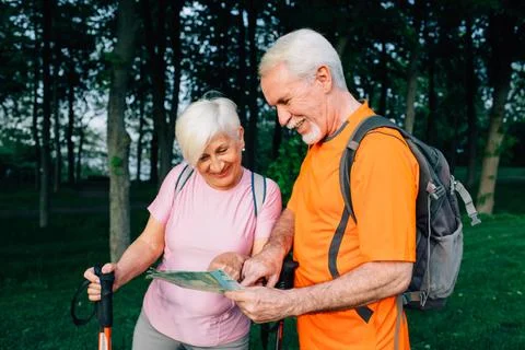 Elderly couple hikers checking map in woods Fotos Stock