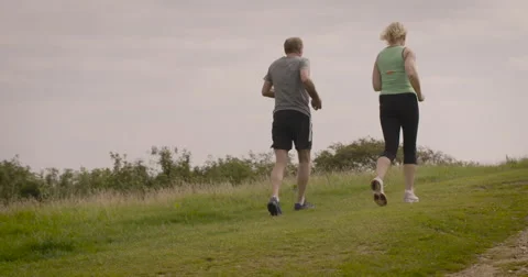 Elderly couple jogging in field Stock Footage 59899765
