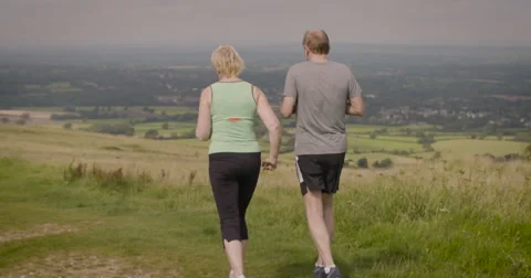 Elderly couple jogging in field Stock Footage 59899792