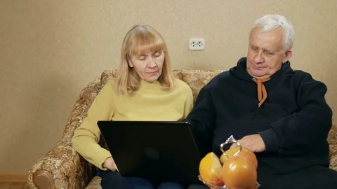 Elderly couple learn how to work with laptop. A man shows how to do it. Woman Stock Footage 71247107