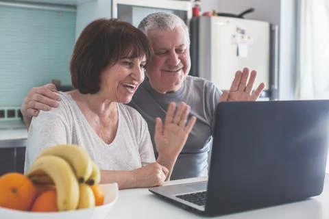 Elderly couple looking at computer in the kitchen Stock Photos