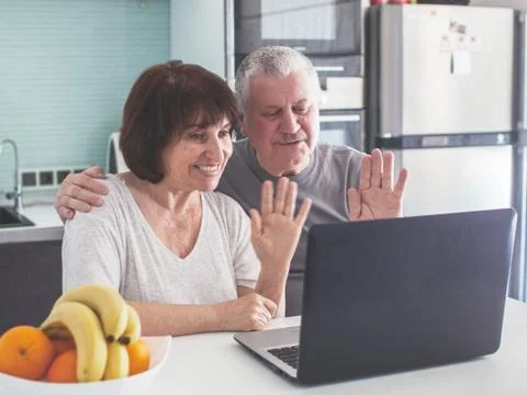 Elderly couple looking at computer in the kitchen Stock Photos