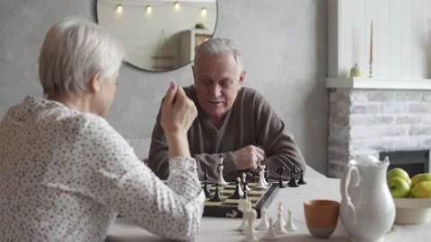 An elderly couple playing chess at the dinner table. Happy elderly couple Stock Footage 172554410