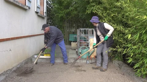 An elderly couple prepares a garden plot near the house for planting vegetabl Stock Footage 153768077