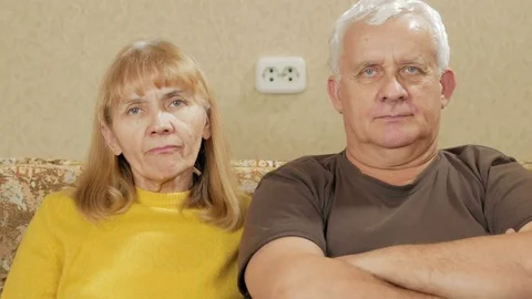Elderly couple resting at home on the couch and looking at the camera Stock Footage 71248075