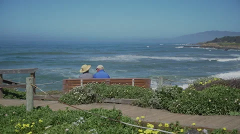 Elderly couple sit on bench in view of ocean Stock Footage 62474916