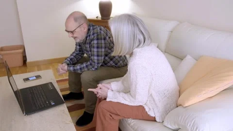 Elderly Couple Sitting on Sofa Looking at Laptop Computer Together Stock Footage 308348947