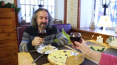 Elderly couple sitting at a table in a cafe and toasting wine glass Stock Footage 83868752