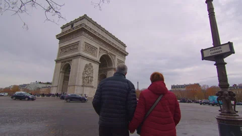 An elderly couple strolls through the streets of Paris with the famous Arc de 스톡 동영상 228104917