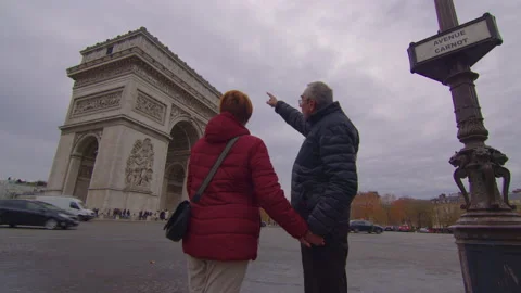 An elderly couple strolls through the streets of Paris with the famous Arc de Stock Footage 228313624