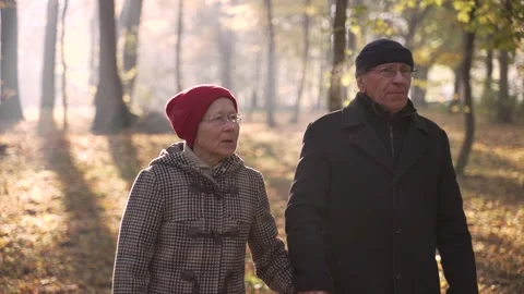 Elderly couple talking while walking around park Видео 168187810