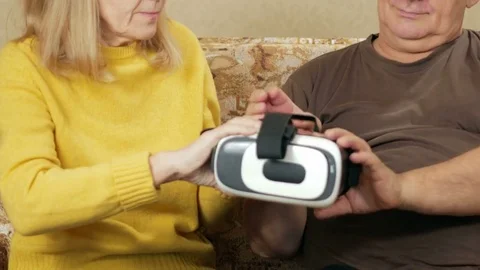 Elderly couple tries glasses virtual reality at home. The man wears glasses and Stock Footage 71247595