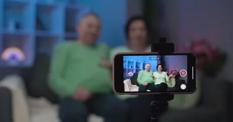 Elderly couple using smartphone video conference with grandchild while lying on Stock Footage 194473818