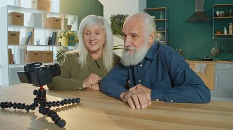 An Elderly Couple Is Vlogging, Making Content For Vlogging in a Cozy Living Room Stock Photos