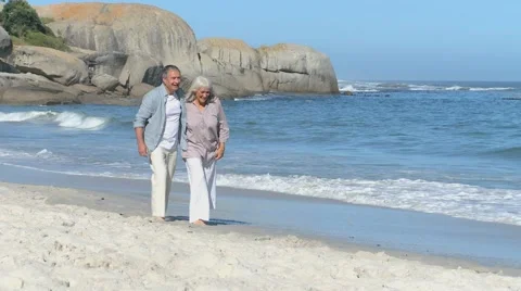 Elderly couple walking along the beach Stock Footage