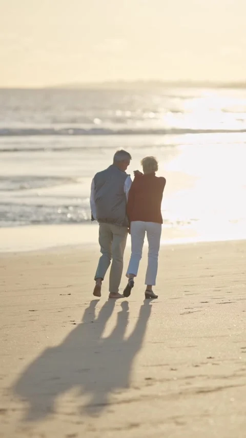 Elderly couple walking on the beach at sunset Stock Footage 327715140