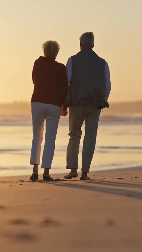 Elderly couple walking on beach at sunset Stock Footage 327715432