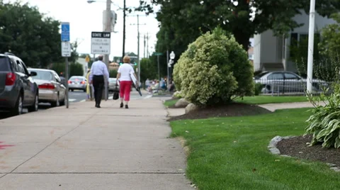 Elderly couple walks down sidewalk with lawn chairs Stock Footage 27623014