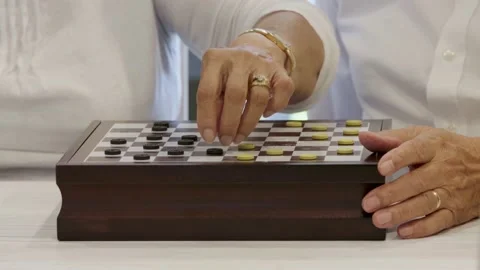 A elderly couple's hands move game pieces as they play a game of checkers. Stock Footage 156721710