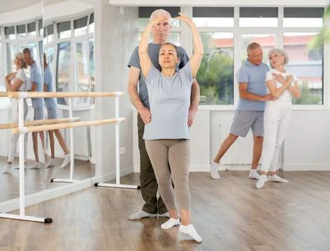 Elderly couples learning to dance ballet in dance studio Stock Photos