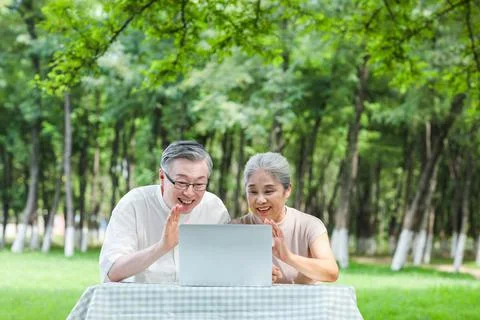 Elderly couples use computer video chat outdoors Stock Photos